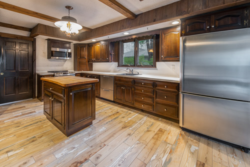 Modern kitchen with dark wood cabinetry, a central island, and hanging pendant lights.