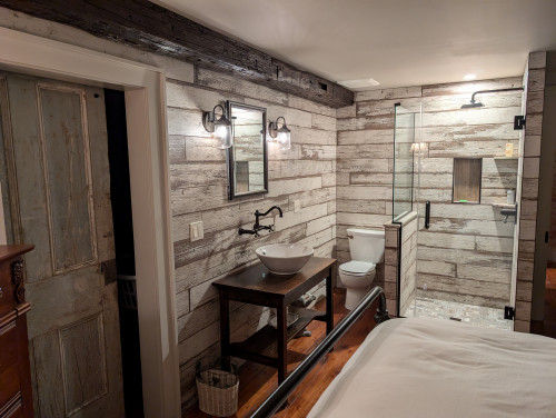 Rustic interior living space with wood-paneled walls, a stone accent wall, and a staircase.